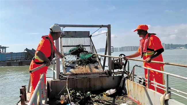 保洁员打捞漂浮垃圾清洁海面。